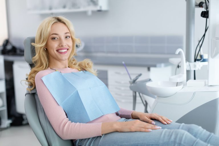 Blonde young woman patient smiling in dentistry, copy space